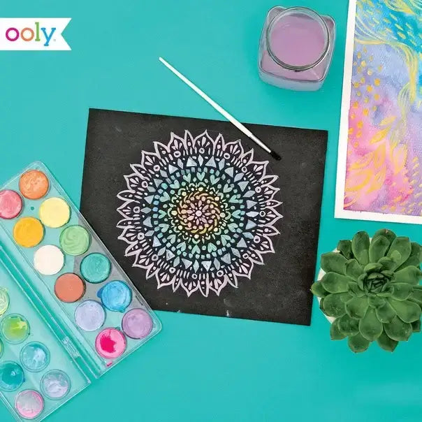 a picture of a mandala on black paper with Prisma water colors on the left