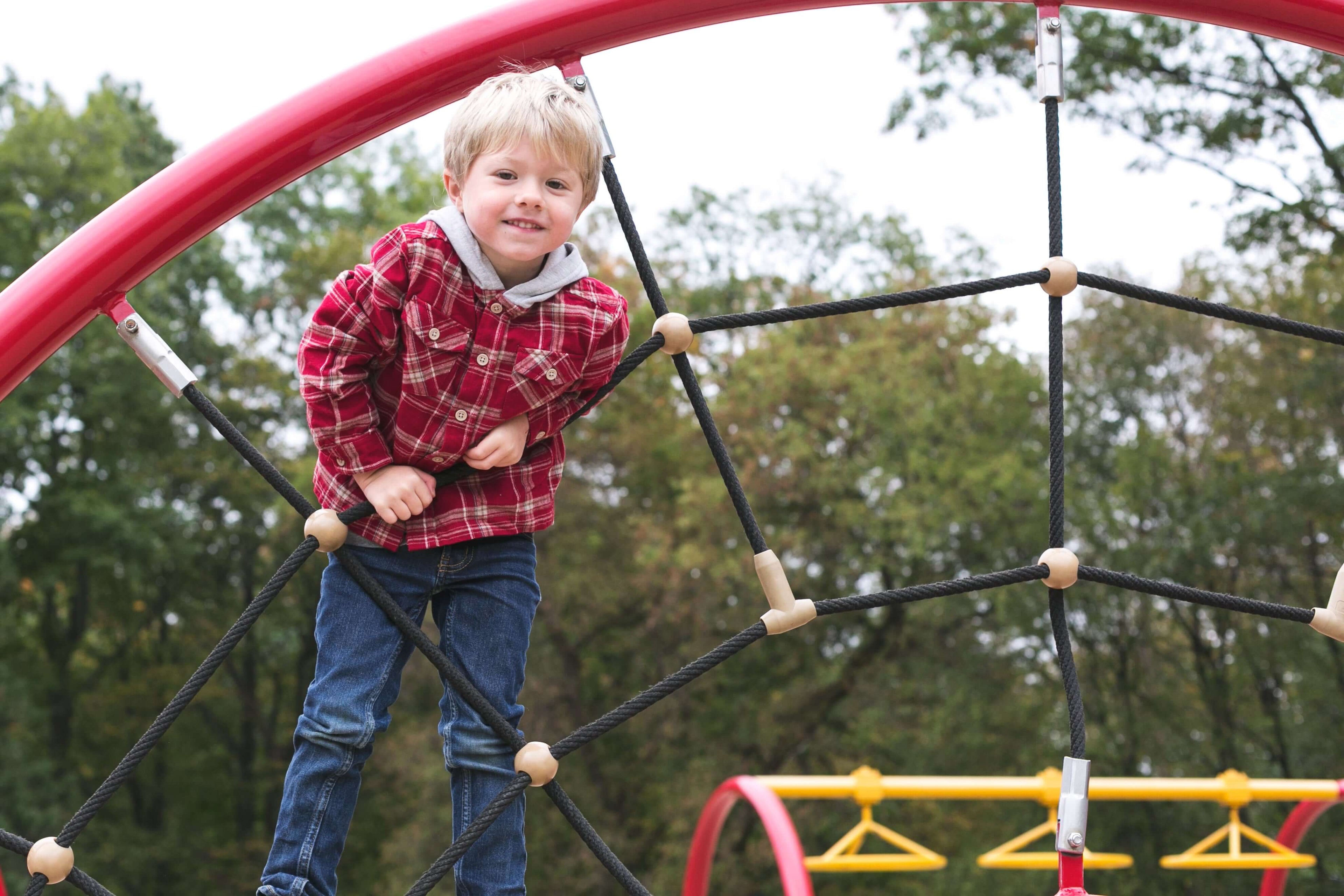boy outside on climbing web