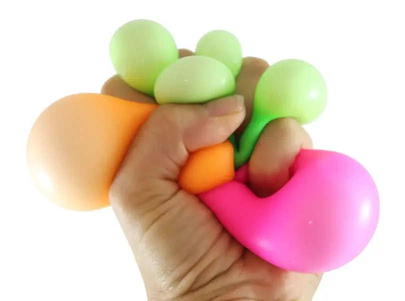 a hand squeezing green orange and pink stress balls